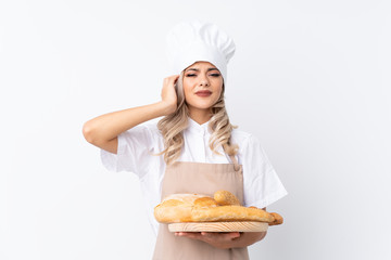 Teenager girl in chef uniform. Female baker holding a table with several breads over isolated white background unhappy and frustrated with something. Negative facial expression