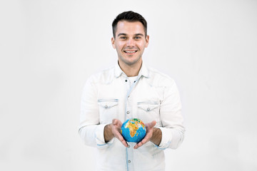 Happy smiling Caucasian hipster man in white casual clothes holding little earth globe against isolated white background. Save Earth, travel concept