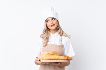Teenager girl in chef uniform. Female baker holding a table with several breads over isolated white...