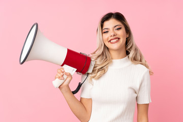Teenager girl over isolated pink background holding a megaphone