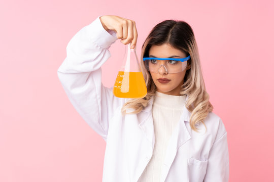 Teenager Girl Over Isolated Pink Background With A Scientific Test Tube