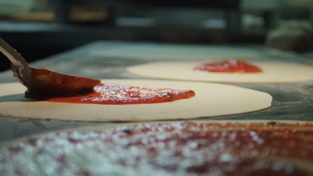 Close up view of a man chef cooking italian pizza. The process of making pizza at table in bakery. Fresh dough on kitchen table