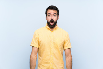 Young man with beard over isolated blue background with surprise facial expression