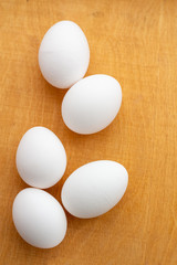 five white eggs lie on a wooden board