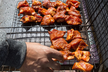 Hands of a man putting meat for barbecue. Close-up image of uncooked meat.