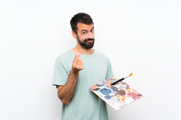 Young artist man holding a palette over isolated background making money gesture