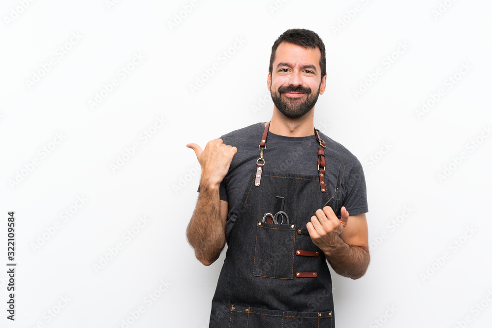 Wall mural Barber man in an apron pointing to the side to present a product