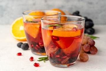 Homemade sangria with orange, grapes and pomegranate seeds in glasses on concrete background. Selective focus.