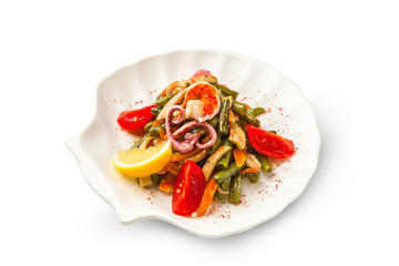 Grilled seafood and vegetables salad decorated with shrimp, octopus and lemon on a white background. fried green beans, bell pepper, carrots and tomatoes on an isolated background