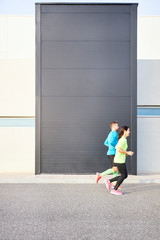 couple of runners running with a modern building in the background