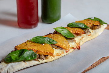 Middle eastern snack with flavors of the Mediterranean. Baked pumpkin, scamorza affumicata cheese, poached eggplant and fresh basil on wooden board and natural juices.