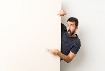 Young handsome man with beard holding a big empty placard and pointing it