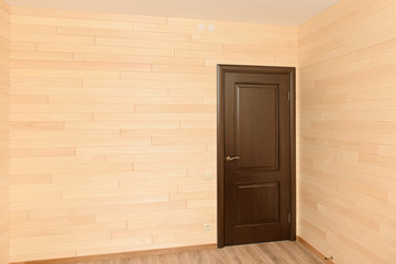 Room interior with a door sheathed by wooden light boards