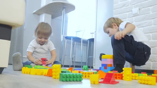 childhood happy family concept little girl and boy brother and sister collects constructor teamwork. child plays toys sitting on floor. children play lifestyle in a team toys on floor in the room