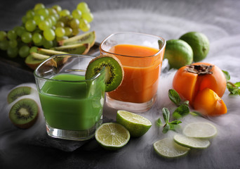 Fruit drinks with persimmon, kiwi, grapes on a dark background. Background image, copy space