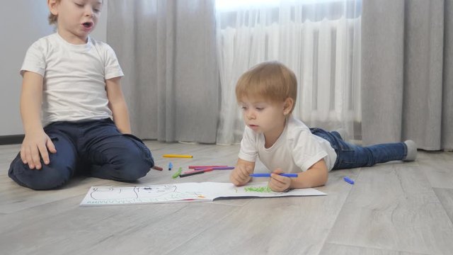 children draw with felt-tip pens in an album. little boy lifestyle and girl concept childhood brother and sister play paint on the floor with colored markers