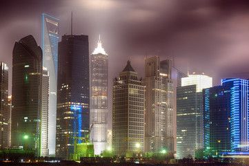 Shanghai's skyline by night, view from Puxi side on Pudong financial center. Illuminated office and hotel skyscrapers by night.