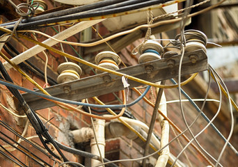 Obsolete electrical network, old wires fixed to brick building facade. Shanghai, China.