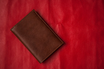 brown leather wallet on red background. Top view, copy space.