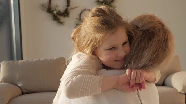 Daughter rushes into mother's arms at home and gives her a big hug.
