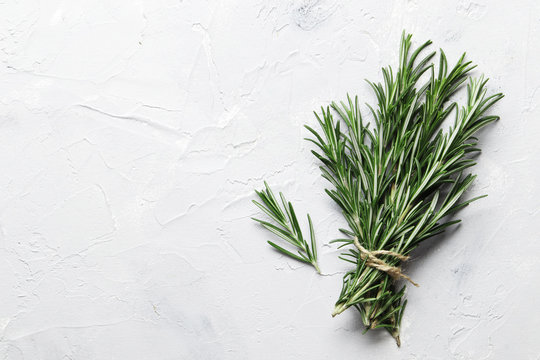 Flat lay composition with rosemary on white concrete background, space for text