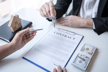 Sale purchase contract to buy a house, Real estate agent are presenting home loan and giving keys to customer after signing contract to buy house with approved property application form