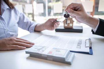 Real estate agent are presenting home loan and giving house, keys to customer after signing contract to buy house with approved property application form