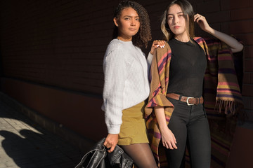 Obraz premium Portrait of two beautiful fashionable Hispanic girls, happy smiling posing for the camera. Autumn street art photo. Y, Z