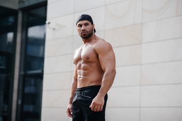 sexy sportsman stands topless near the wall. Fitness, bodybuilding