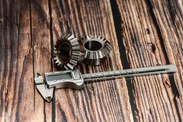 Two bevel gears and vernier caliper on a wooden background.