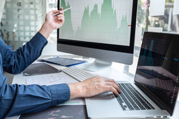 Businessman investor working in traders marketing and planning and analyzing pointing on the stock chart data presented and deal on a stock exchange to business profit