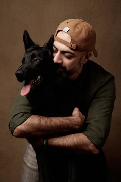 Cheerful Young Man Hugging His Dog, Indoors Portrait