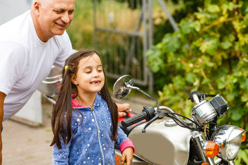 Obraz premium happy grandfather and his granddaughter near bike smiling