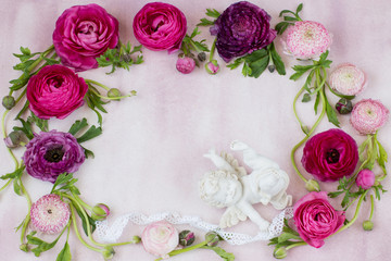 on a pink background, the frame is lined with ranunculus and a figure of a white angel