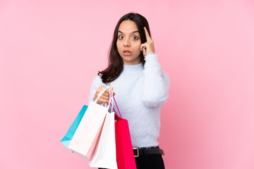 Young woman with shopping bag over isolated pink background thinking an idea