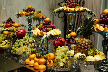 Fresh organic fruits background. Healthy eating concept. Fresh, exotic, organic fruits, light snacks in a plate on a buffet table. Luxury wedding catering. Delicious fruit at wedding reception.