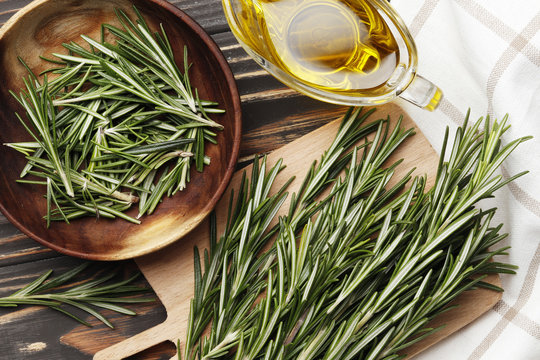Flat lay composition with fresh rosemary, spices, oil on wooden background, space for text