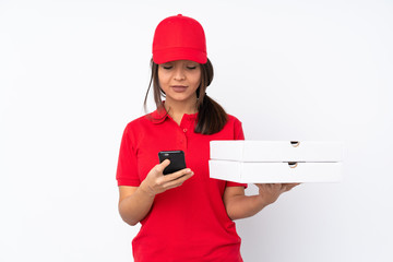 Young Pizza delivery girl over isolated white background sending a message with the mobile