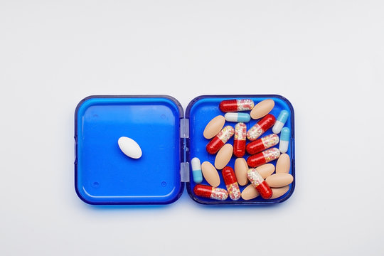container with different capsules and tablets on a white background, concept image.