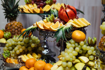 Background of fresh fruit. Fresh organic fruits background. Healthy eating concept. Fresh, exotic, organic fruits, light snacks in a plate on a buffet table. Fruit at the buffet.