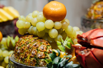 Background of fresh fruit. Fresh organic fruits background. Healthy eating concept. Fresh, exotic, organic fruits, light snacks in a plate on a buffet table. Fruit at the buffet.