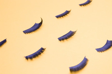 several pairs of different false eyelashes on a yellow background copy space top view, fluffy black eyelashes, pattern of eyelashes