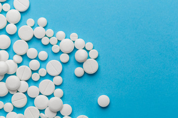 scattered white pills on a blue table. Layout for special offers such as advertising or other ideas. The concept of medicine, pharmacy and healthcare. Space for copy. flat lay for text or logo.