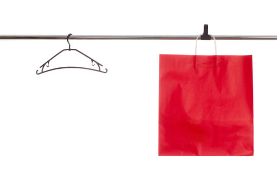 Red paper bag on white background isolate on a hanger and an empty platik hanger next to it