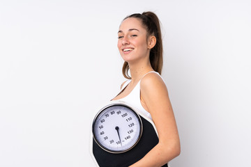 Young brunette woman over isolated white background with weighing machine