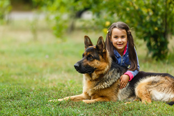 Pretty little girl, Gives a command to sit to german shepherd dog.