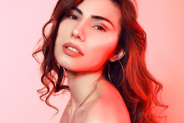 Gorgeous brunette with wrap hair portrait. Girl on a pink-red background. Beauty portrait of a girl. Professional makeup, perfect eyebrows, large lips.