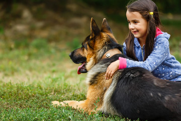 Pretty little girl, Gives a command to sit to german shepherd dog.