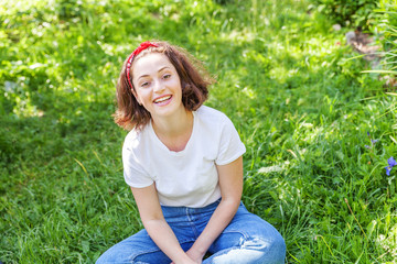 Happy girl smiling outdoor. Beautiful young brunete woman with brown hair resting on park or garden...