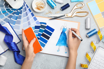 Fashion designer with color palette drawing dress at marble table, top view